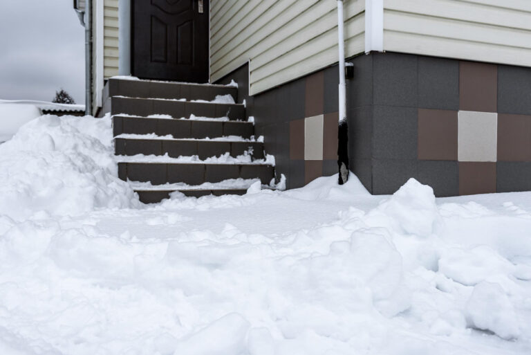 Concrete driveway with visible surface cracks and pits showing signs of freeze-thaw stress.